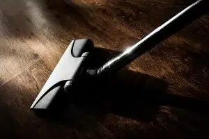 Close-up of a vacuum cleaner head on a polished dark wood floor