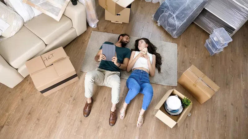 Couple relaxing after moving in, surrounded by unpacked boxes