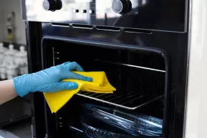 Professional cleaner wiping oven racks with microfiber cloth in Singapore