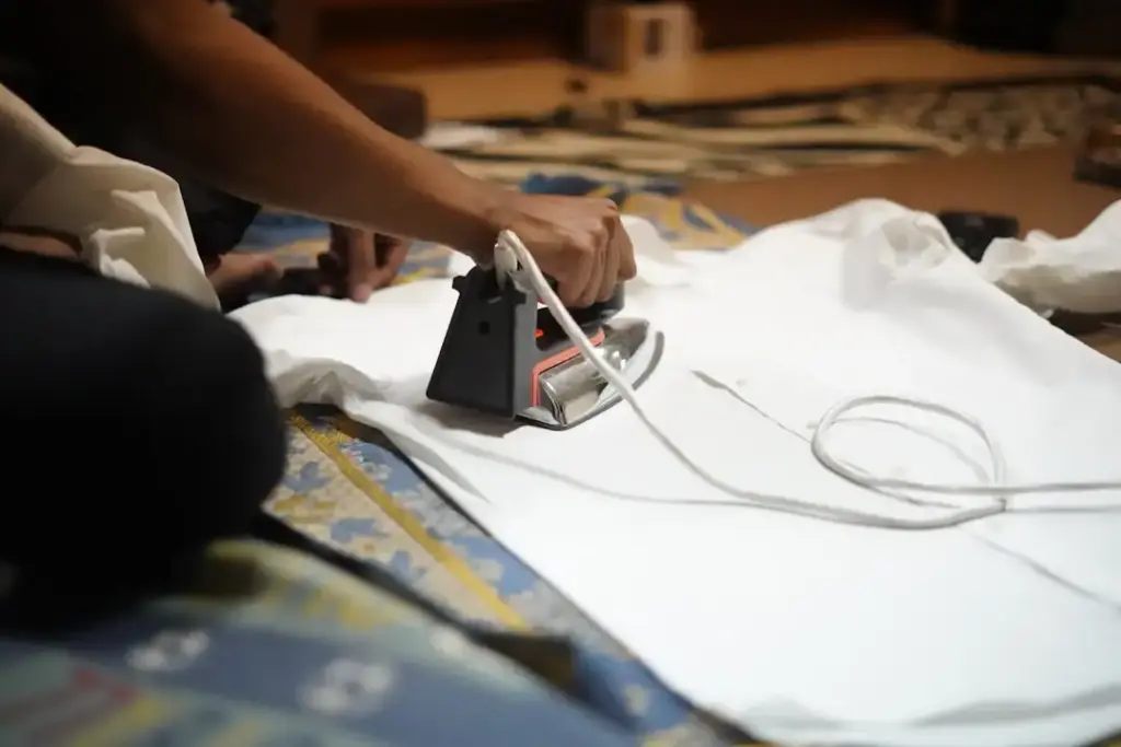 Hand ironing a white shirt on ironing board