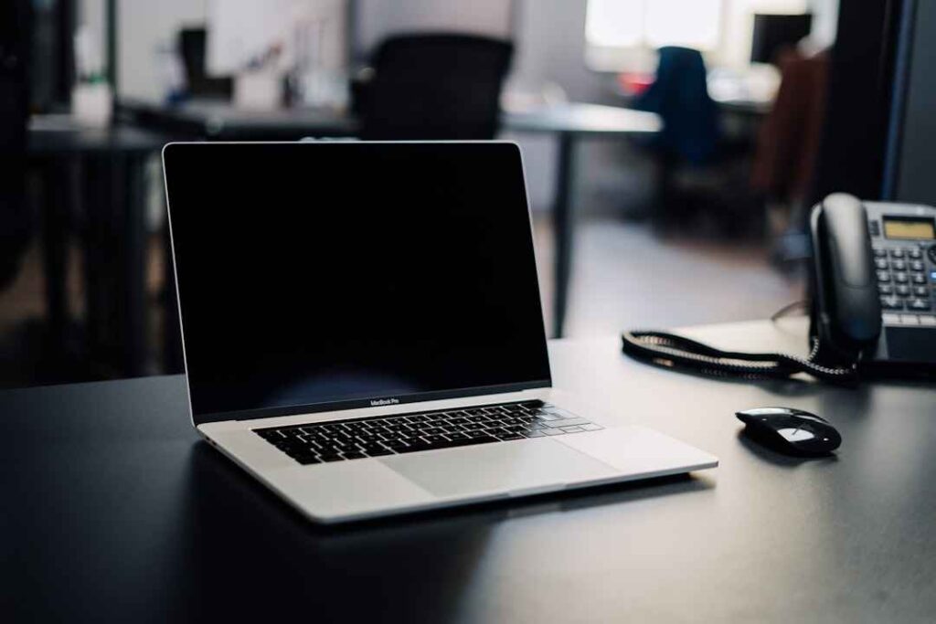 Laptop on an office desk with phone and mouse
