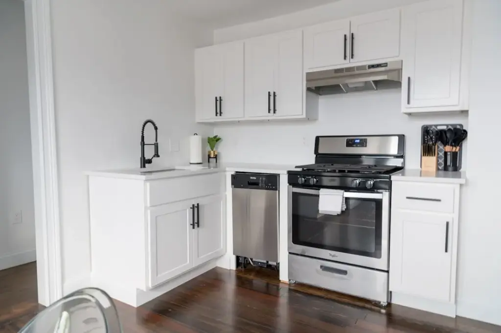 Modern white kitchen with sink, stove, and cabinets