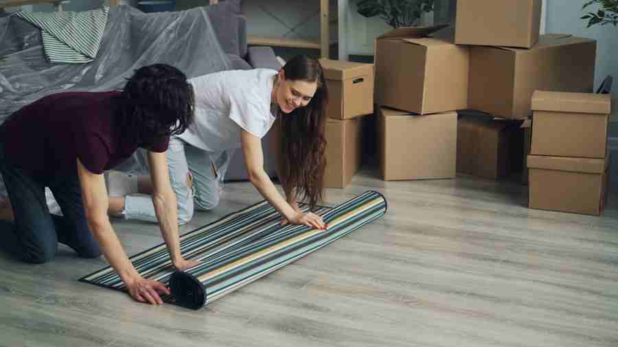 Homeowners rolling up a carpet while preparing a home for moving and cleaning in Singapore